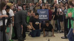 Dr. Nikos keeps time for two students racing their Mousetrap car as the audience looks on.