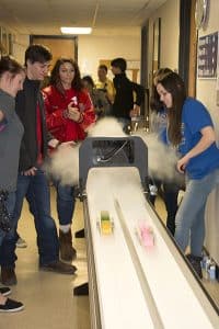 Visiting students stand on the left of the car track as McNeese students on the right control the car race.