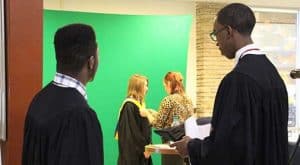 Students stand in line to have their cap and gown photo taken