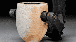 A stone cup is gripped by a piece of machinery