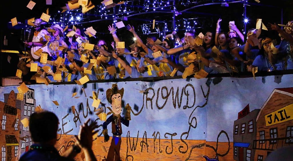 Students tossing candy and toys from moving parade float to the crowd.