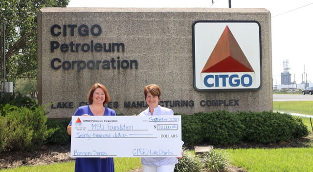 Patricia Prudhomme of Banners accepts a check from Dana Keel of CITGO in front of CITGO sign.