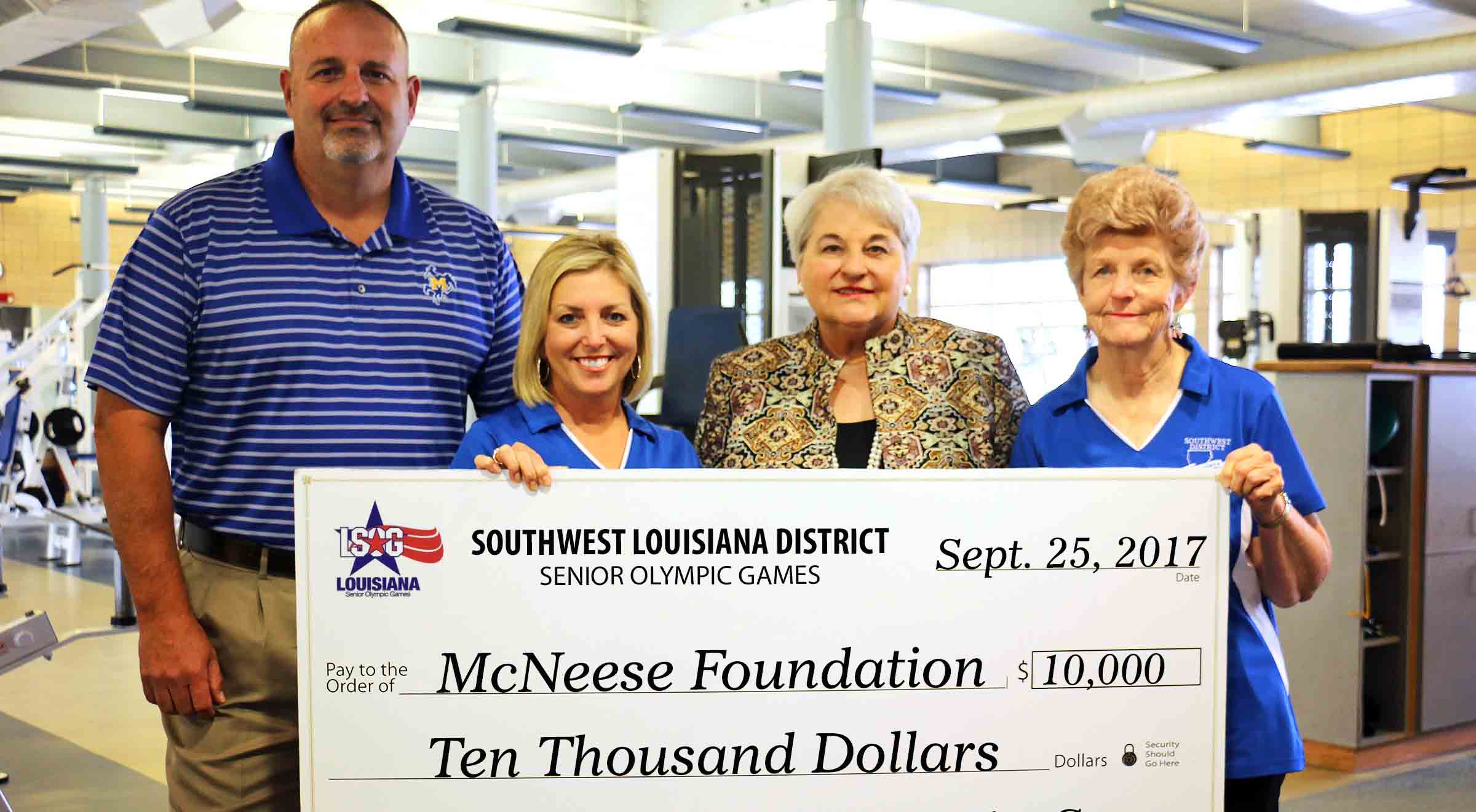 Senior Olympic Games members present a check to McNeese members in the Rec Center weight room.