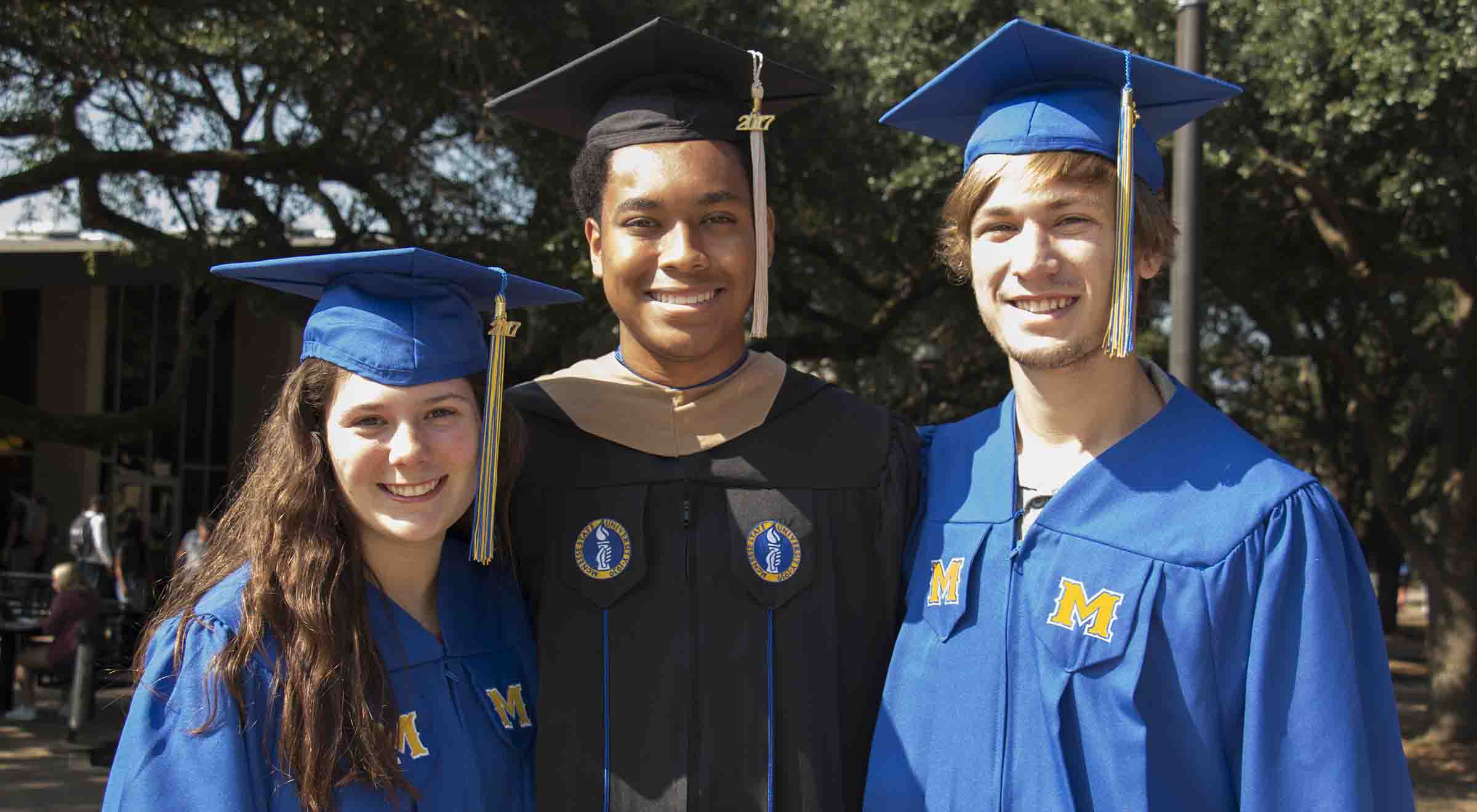 Students standing with new blue and black graduation robes.