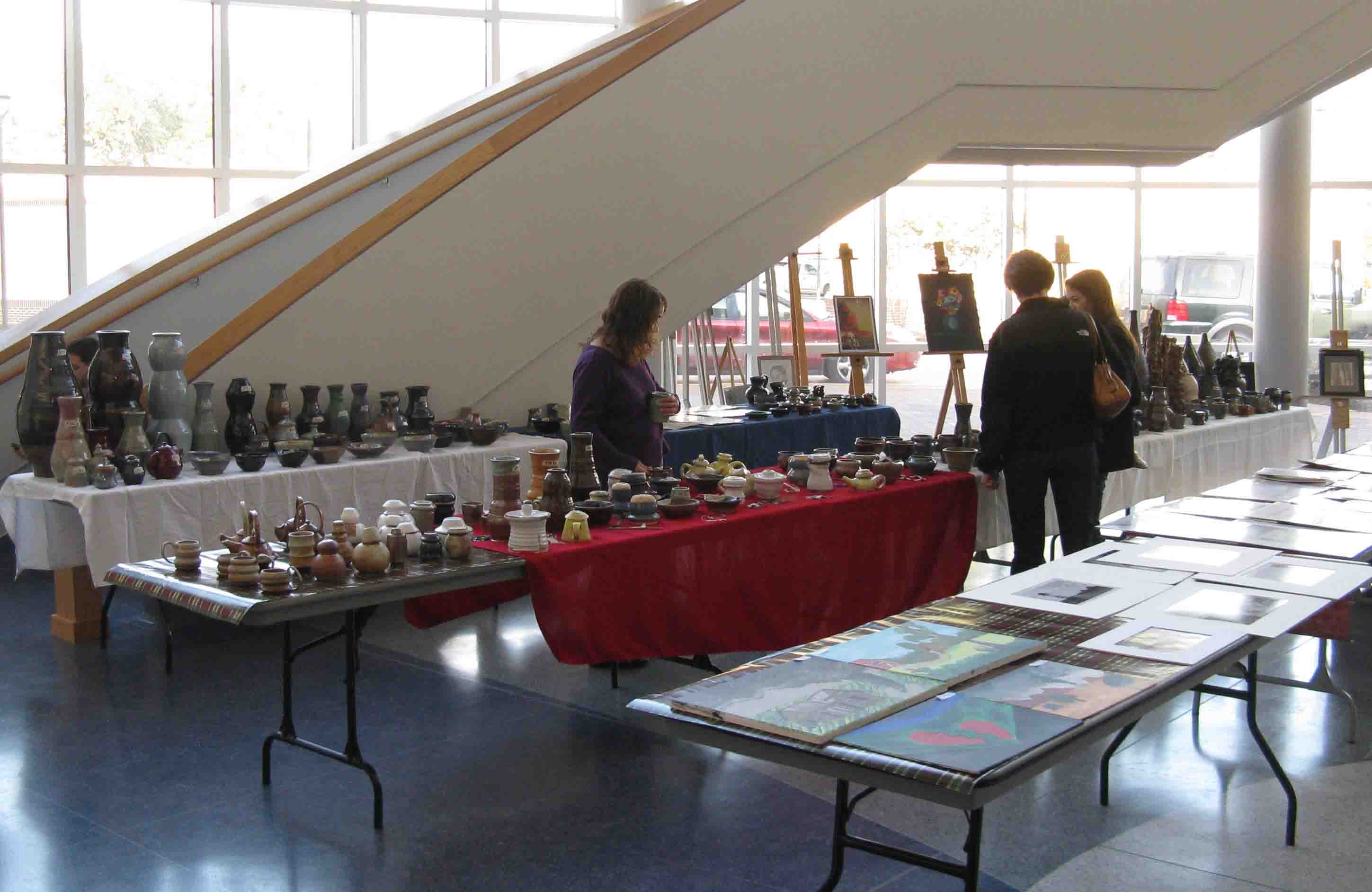 Art sale visitors admire student work on display.