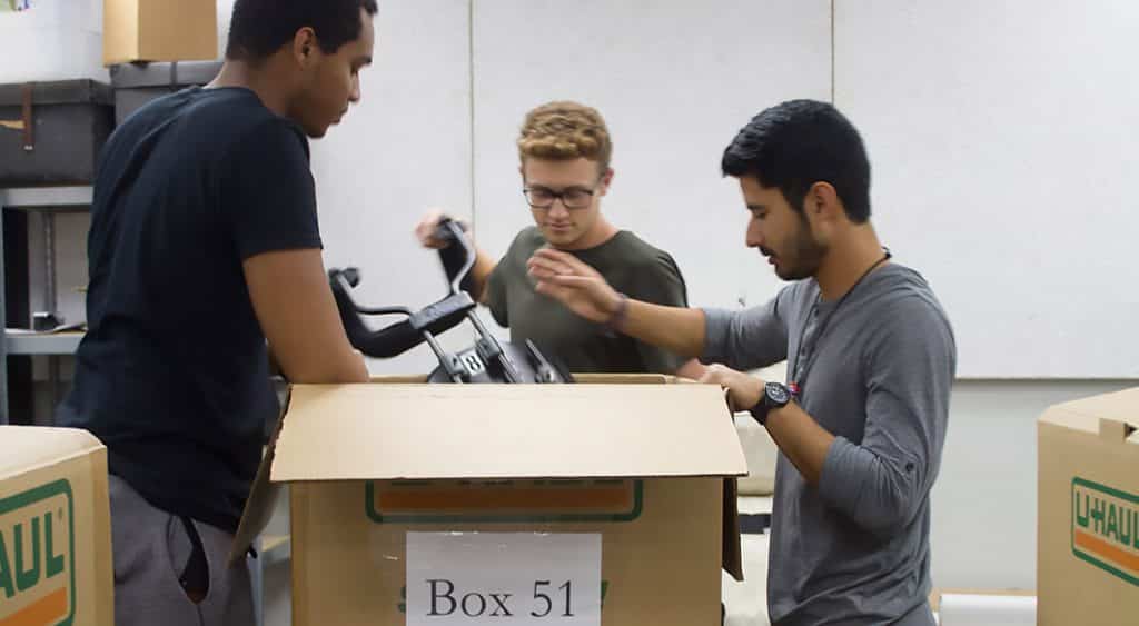 Austin Young, Ty Ellender, and Joseluis Botello-Esquivel of McNeese pack instruments into a large box.