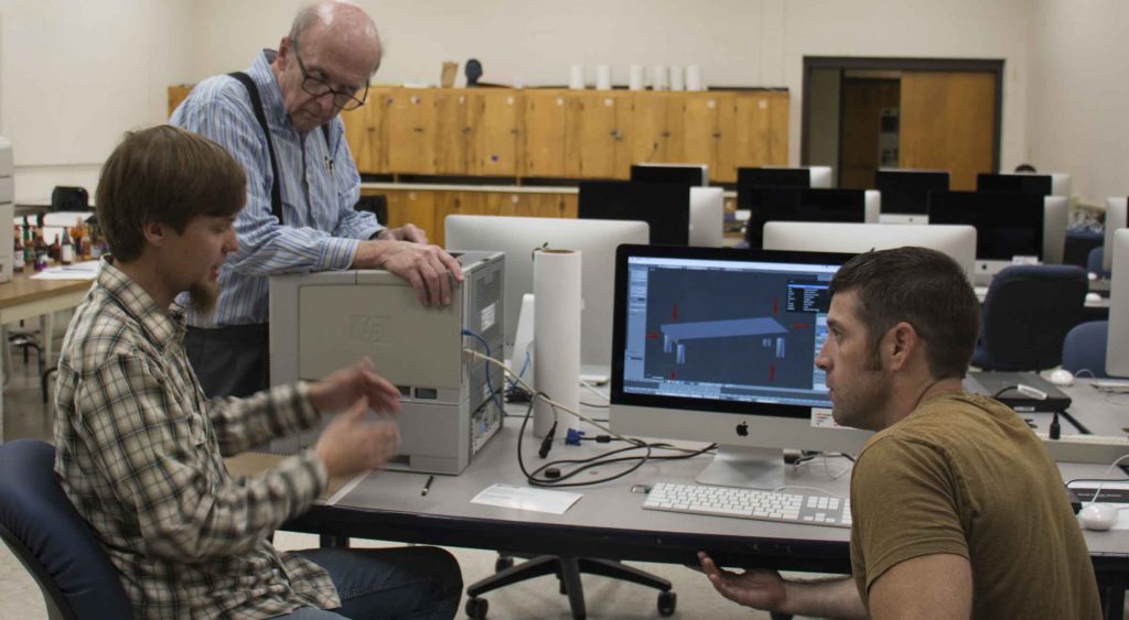 Professor Martin Bee stands with students as they work on a project.