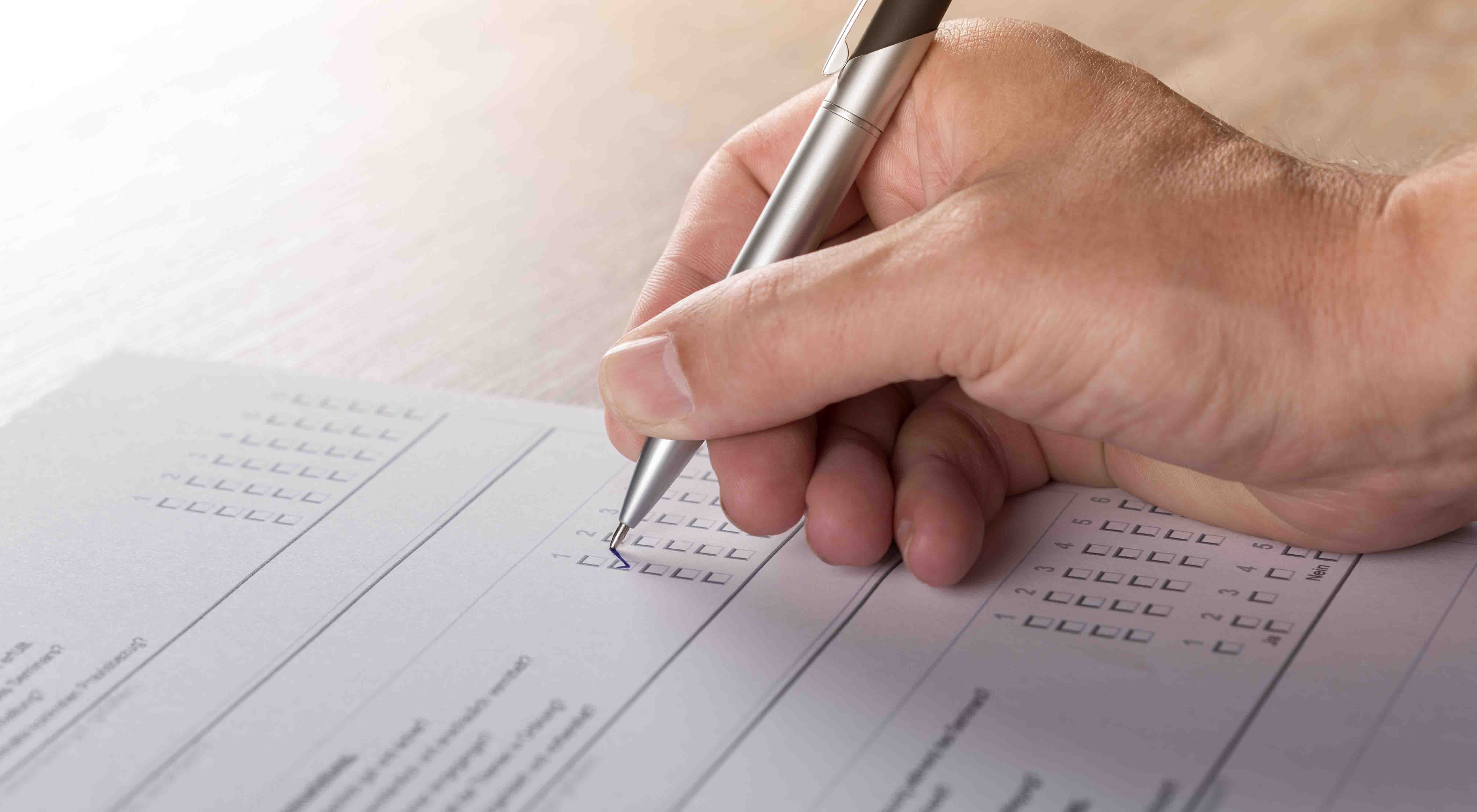 A hand is seen using a pen to mark on a test paper