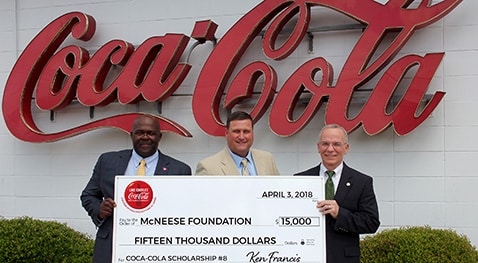 Ken Francis and Blaine Royer of Coca Cola stand with Eddie Meche of McNeese for the check presentation.