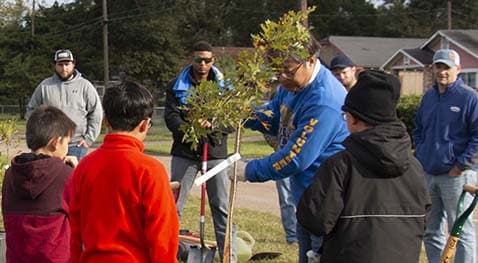 Volunteers watch how to dig and plant tree species.