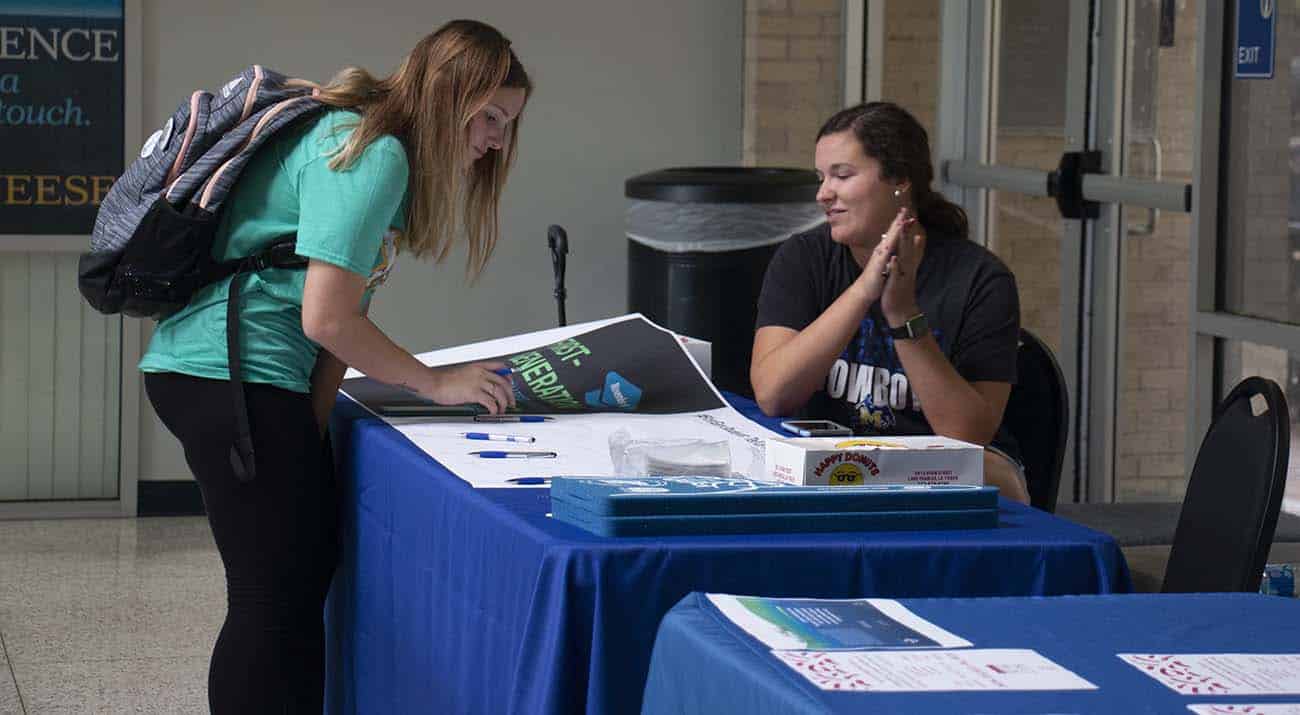 2019 First Gen A student signs her name on the First Generation banner.