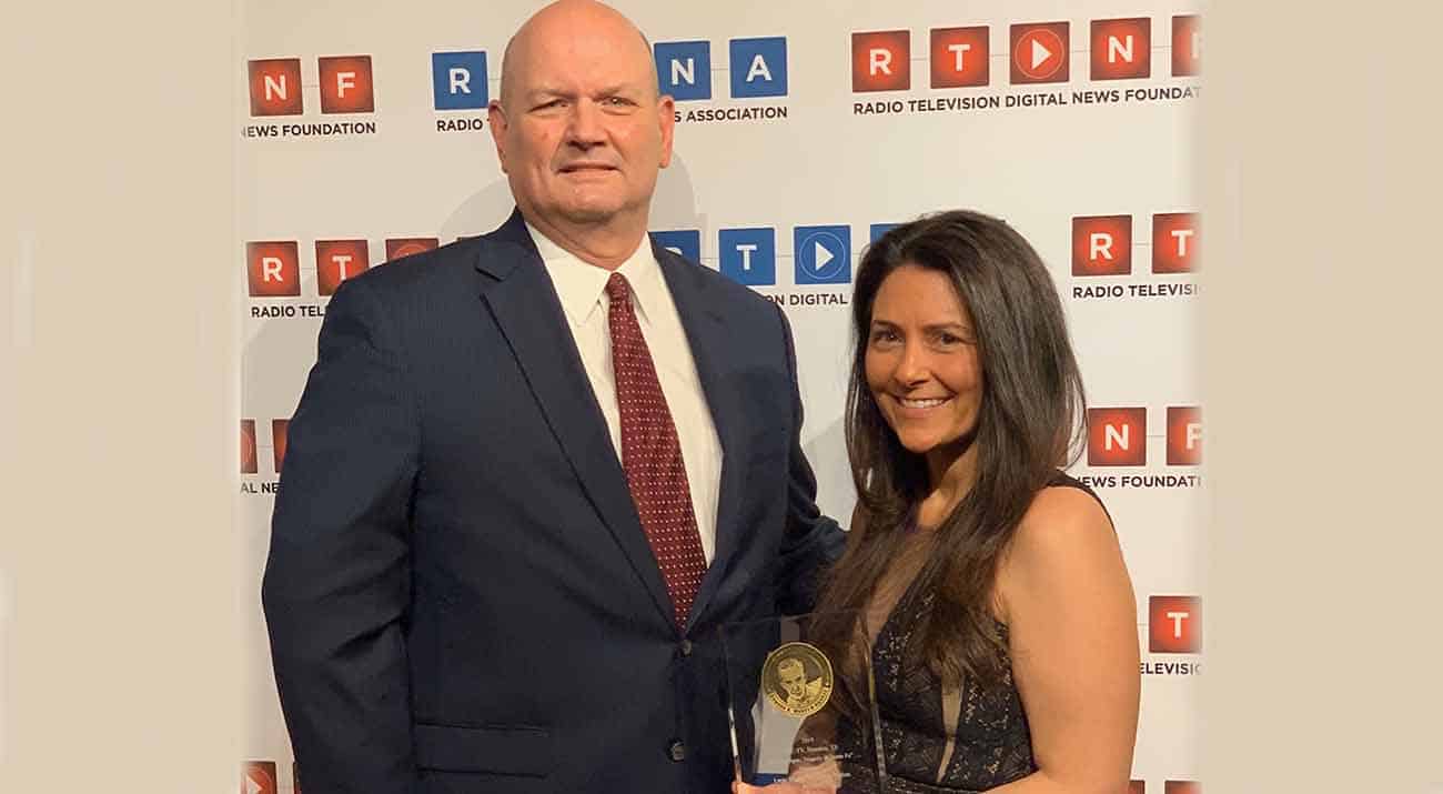 Erica Young stands with her supervisor while holding her award.