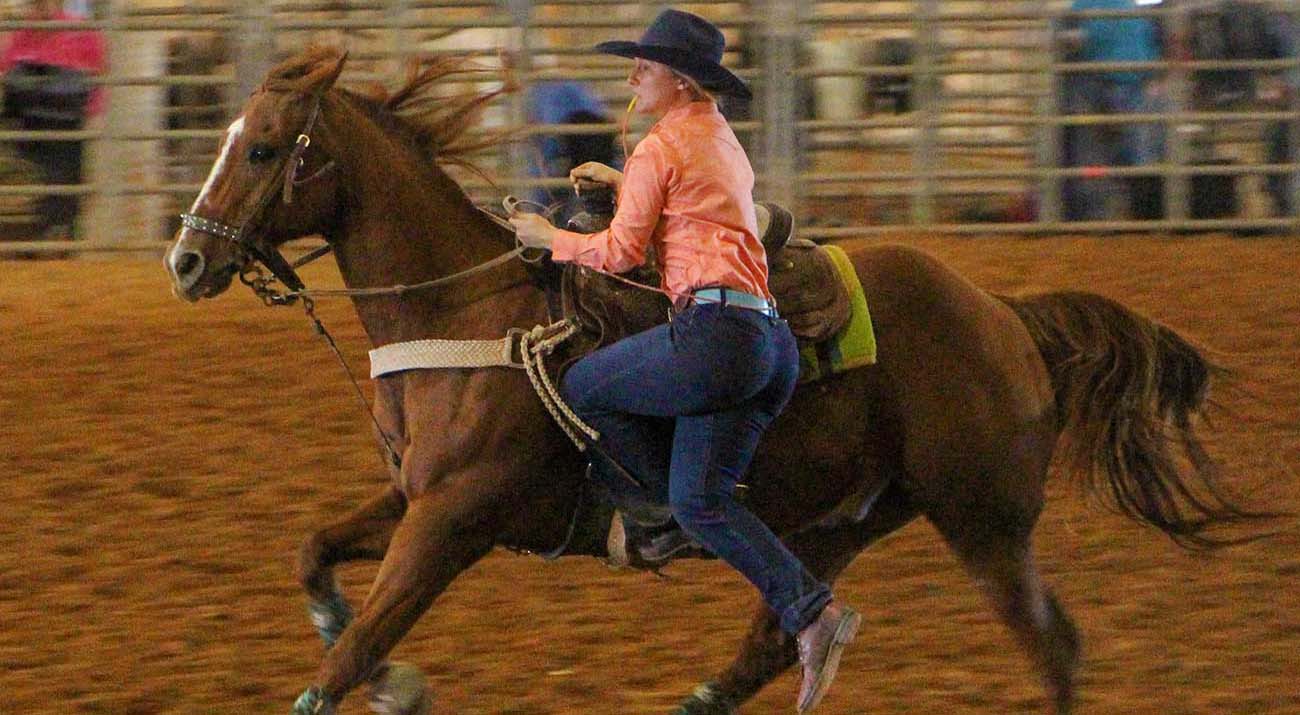 A rodeo team member descends from a horse to finish the event.