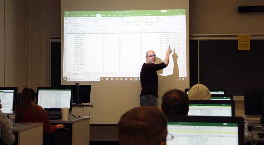 Dr. Lonnie Turpin points on data points on the project screen to a class of students.