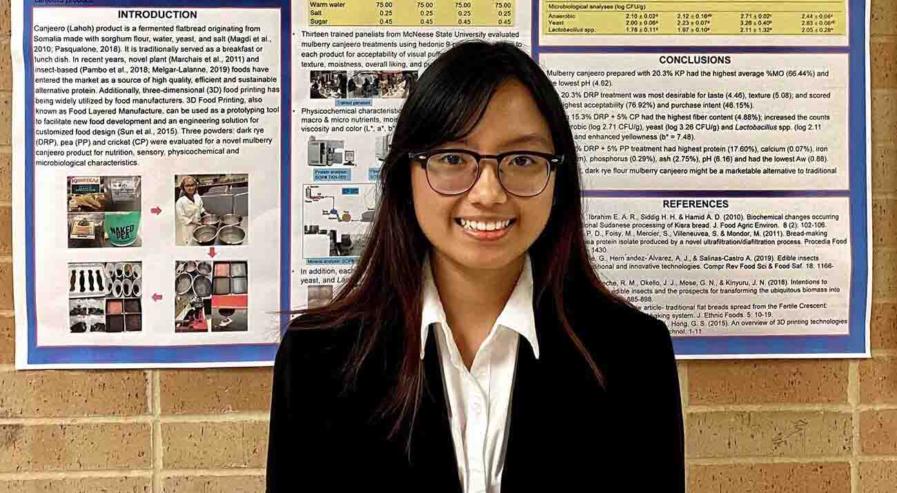 Oanh Vuong stands in front of her poster with graphs and photos the illustrate her research.