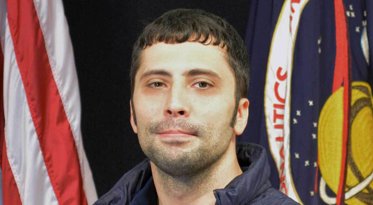 Kevin Romero in front of an American flag and the nasa flag