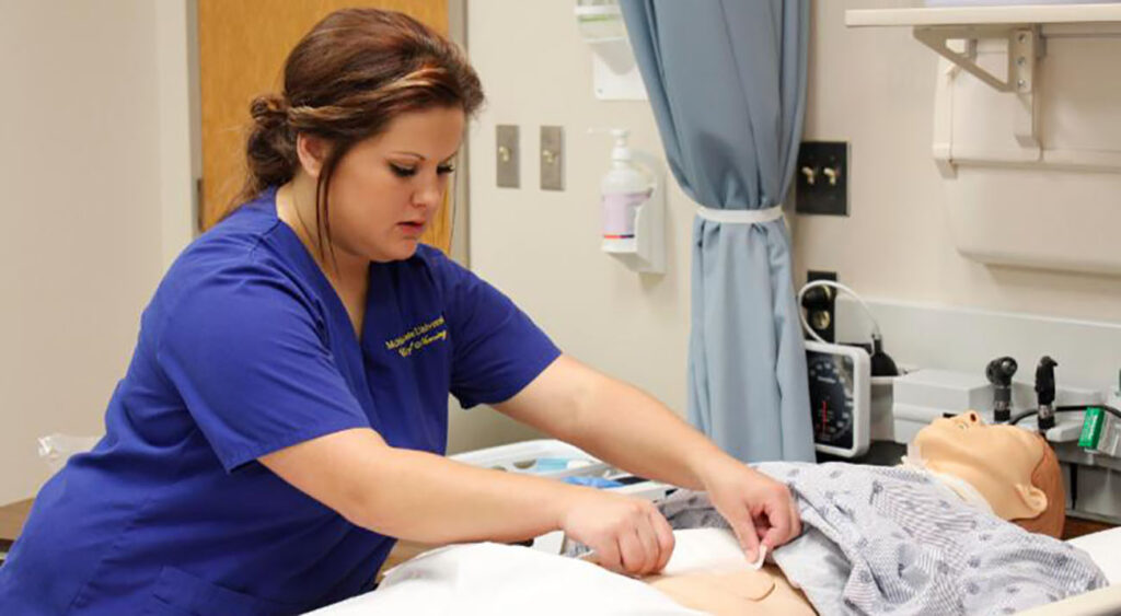 A nursing student uses a mannequin to practice her skills.