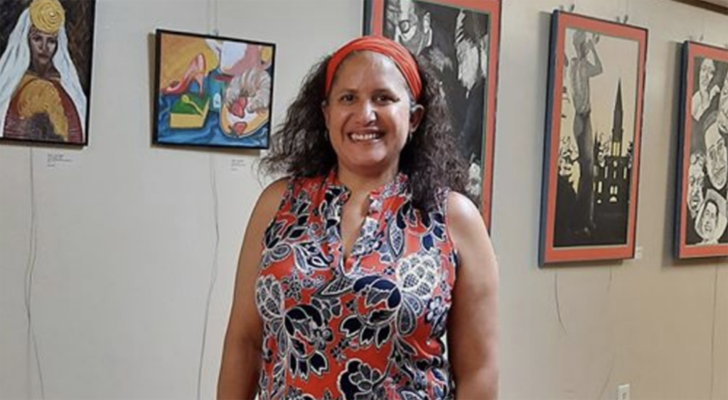 Lisa Wyatt stands in front of several pieces of her art.