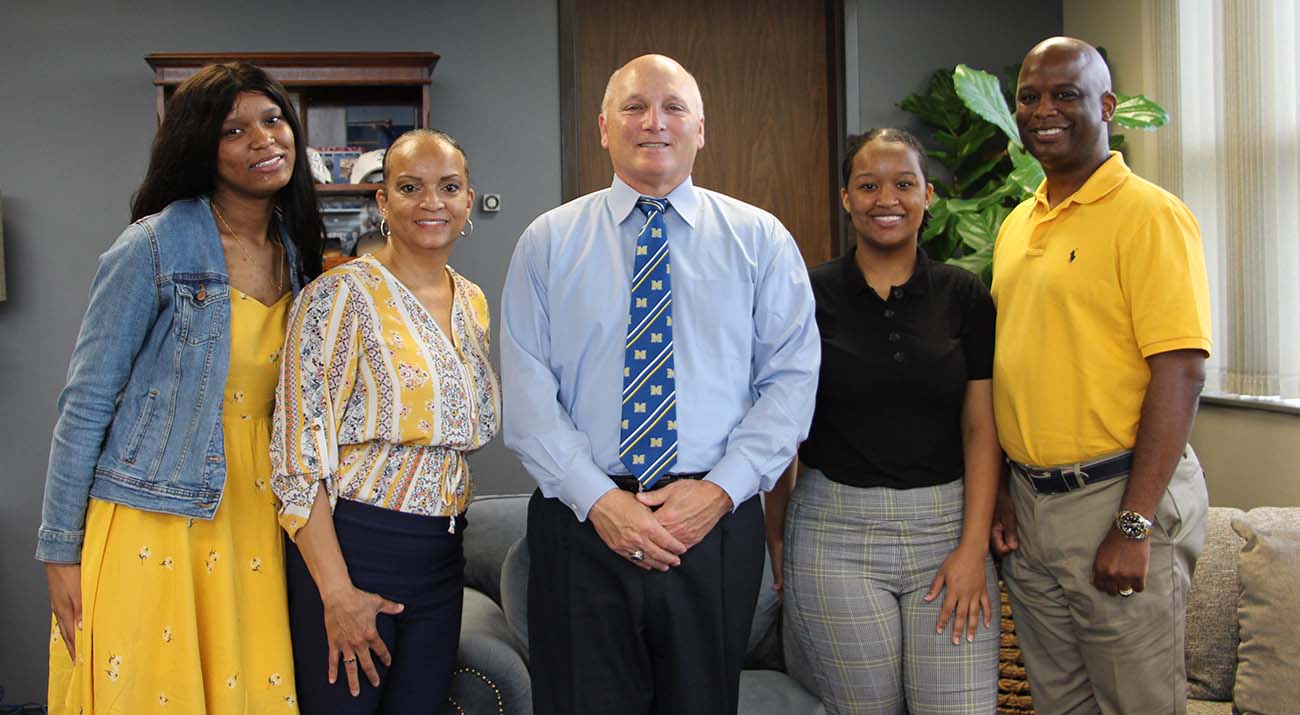 McNeese President Dr. Daryl Burckel stands with the Ned family in his office.