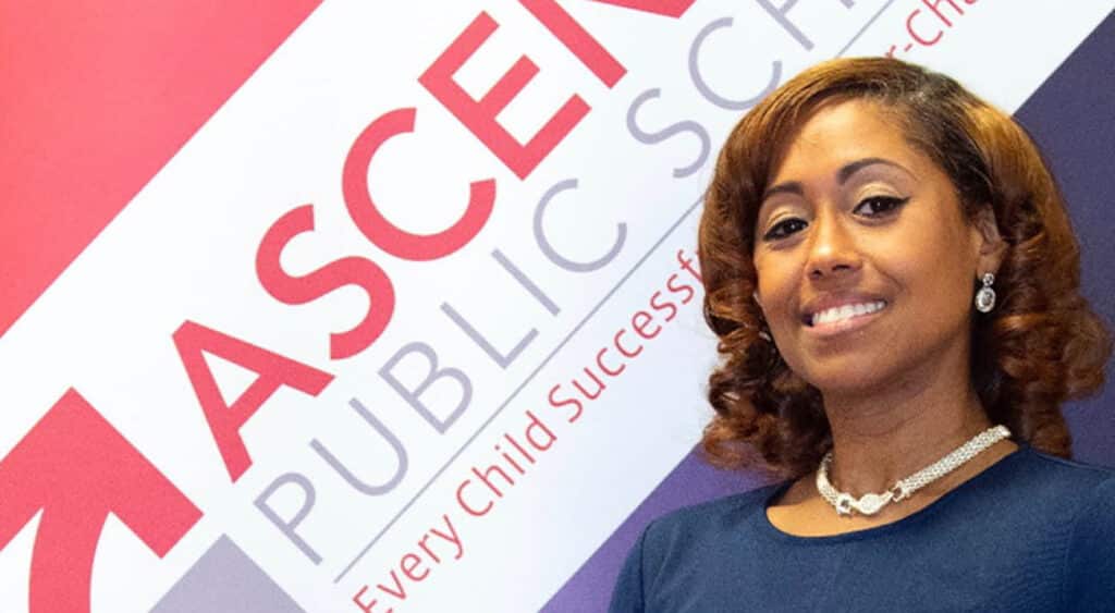 Moquita Winey stands in front of a red white and blue banner for Ascension Parish Schools