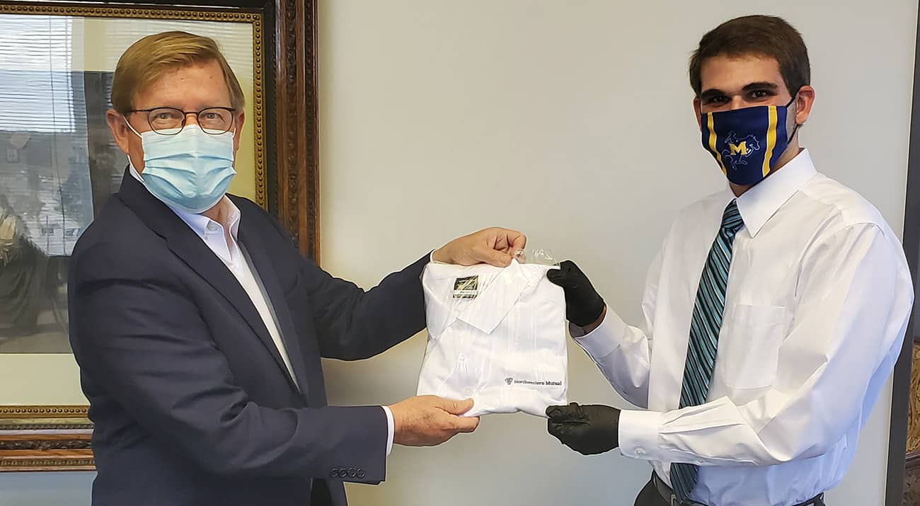 Zeb Bellimen, right, completed his internship with Northwestern Mutual and now works full time at the firm. Ted Harless, Northwestern Mutual Managing Director, left, presents Zeb a company shirt to welcome him to the team.