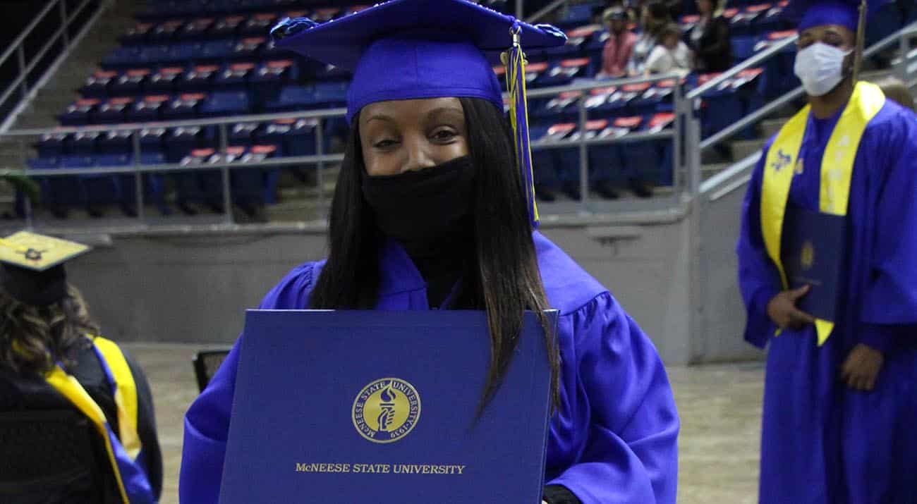 A young lady stands with her diploma cover.