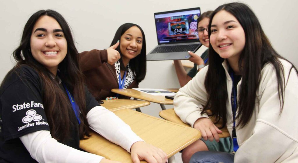 Four students show off their completed computer task