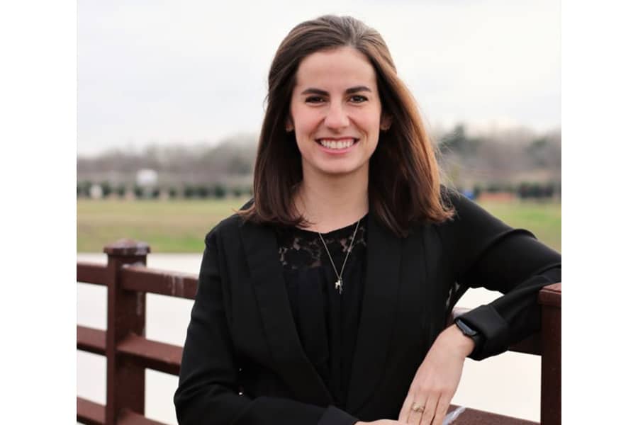 Smiling woman in black jacket leaning on wooden railing outdoors