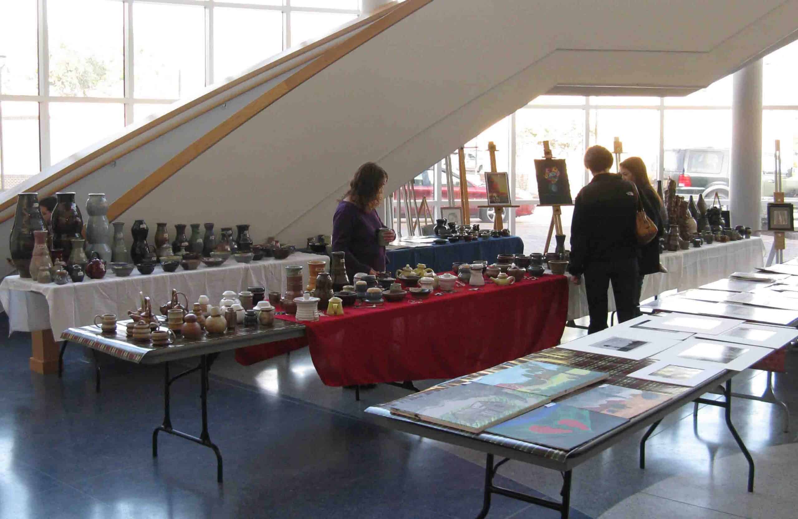 Art sale visitors admire student work on display.