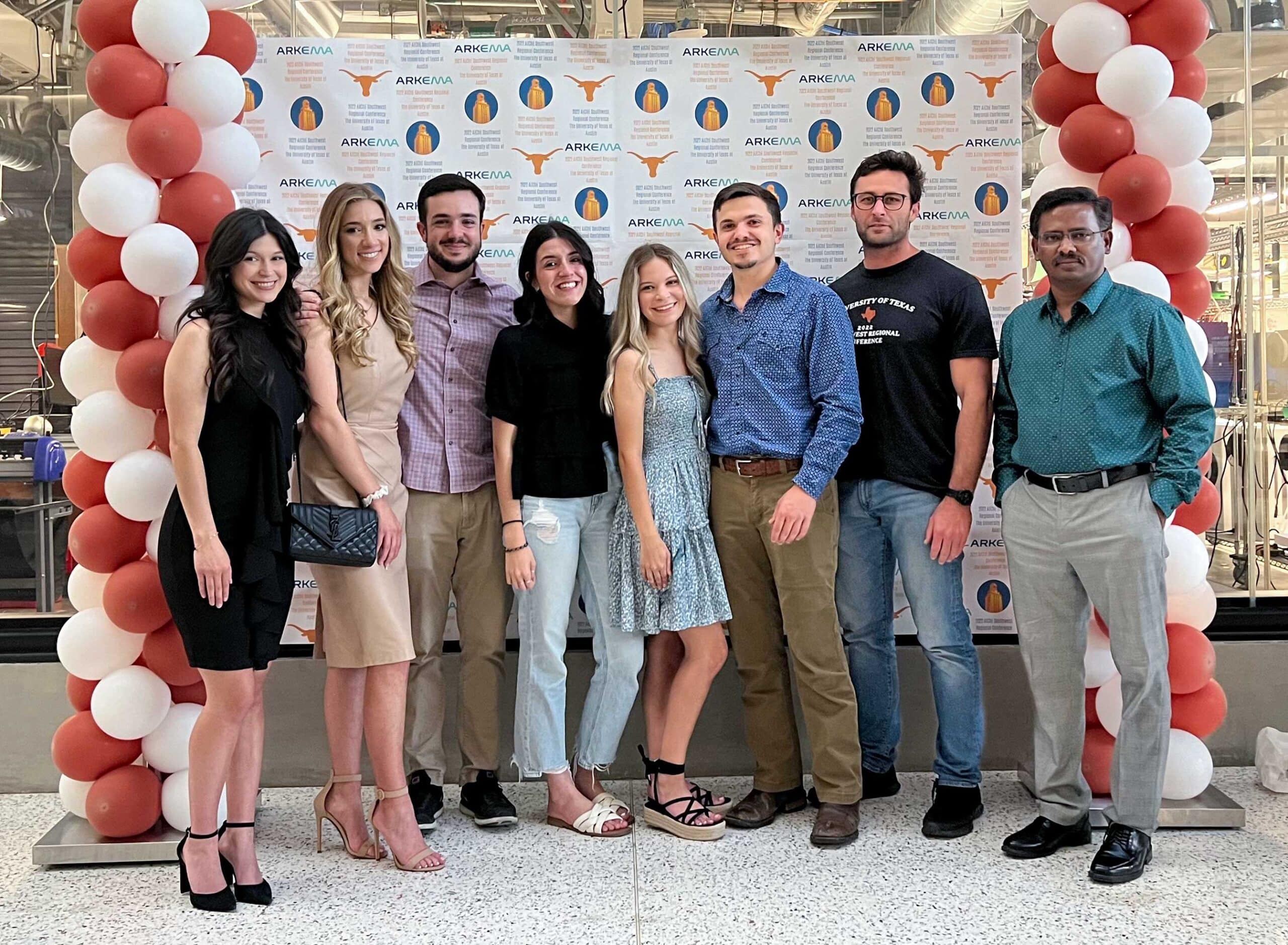 Group of eight people smiling, standing in front of a backdrop with Arkema and University of Texas logos, flanked by balloons.