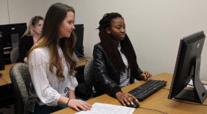 VITA intern Osauwen Osagie helps McNeese student Hannah Maust with her tax return.