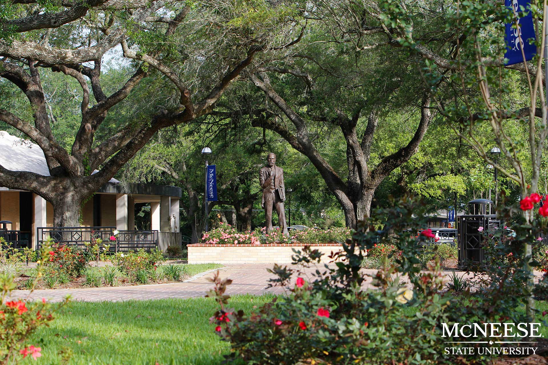 Statue surrounded by trees and flowers at McNeese State University campus.