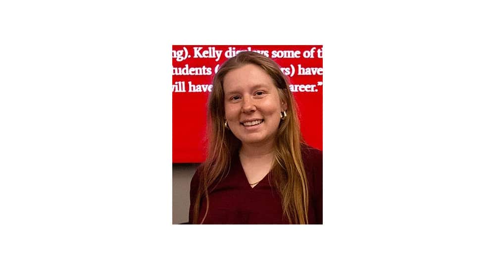 McNeese Alumna Kelly Hines smiling and standing in front or a red background.