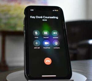 Smartphone displaying active call screen with 'Kay Doré Counseling' and call options.