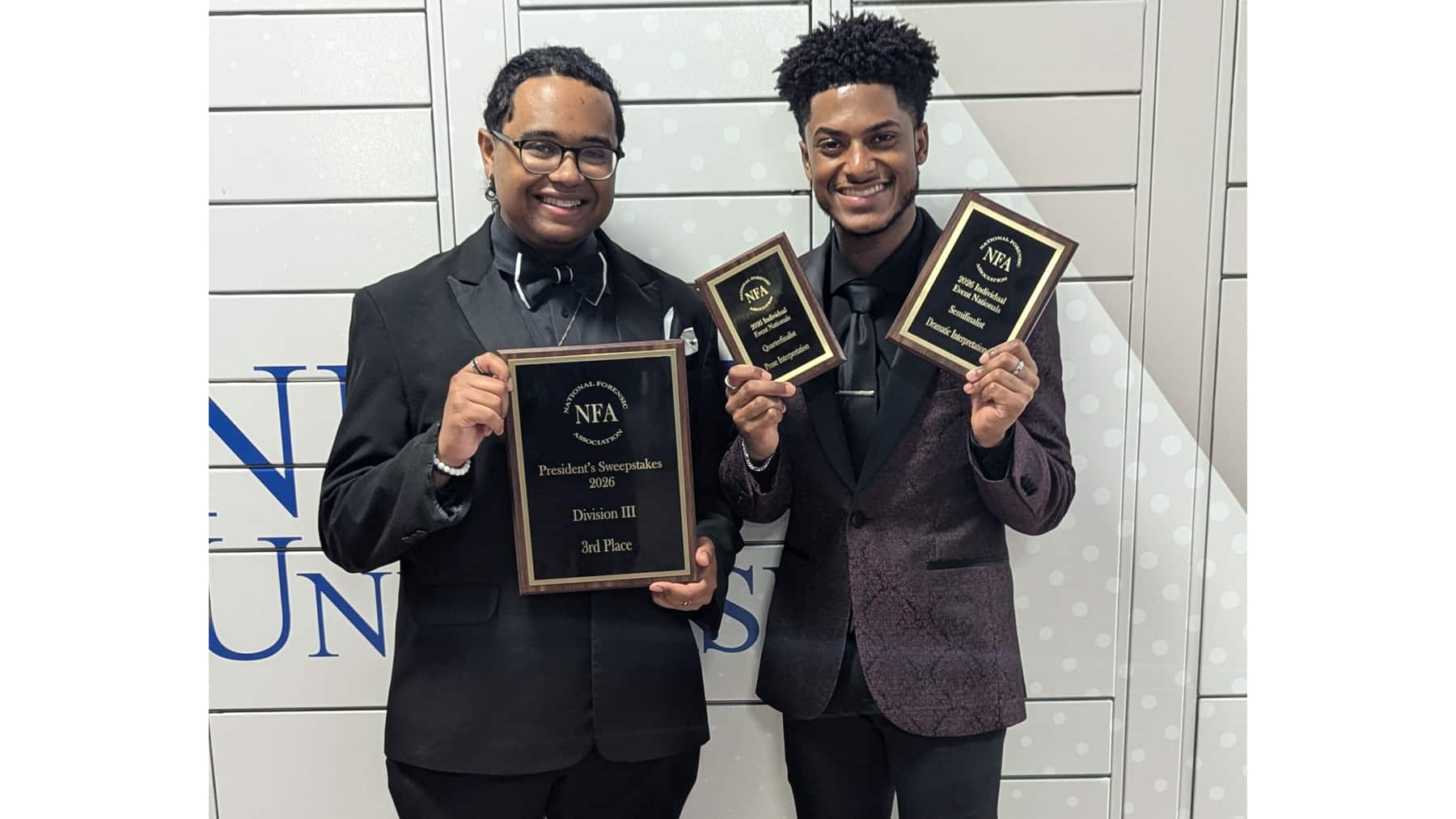 McNeese students dressed in black suits hold up plaques they won in a speech and debate tournament.
