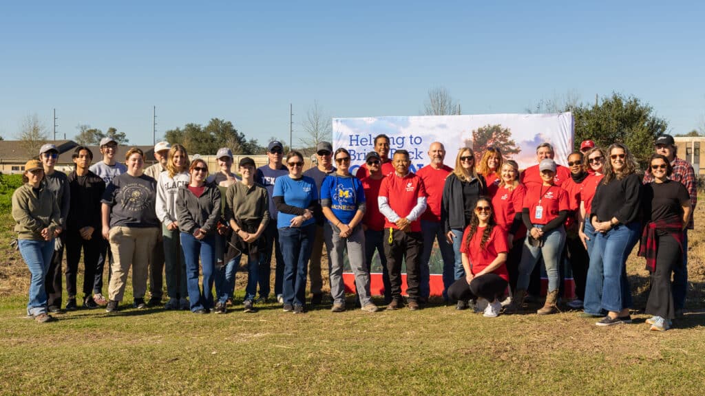 McNeese faculty and students with Woodside Energy employee volunteers stand together in front of the Cajun Prairie sign.