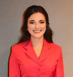 Smiling woman in a red blazer posing against a neutral background