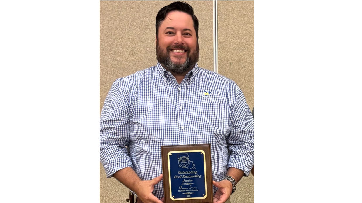 McNeese student smiling and holding an award plaque.