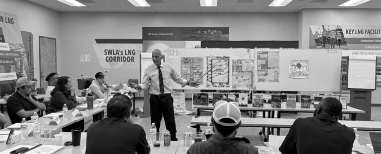 Instructor presenting to a group in a classroom with diagrams on LNG corridor.