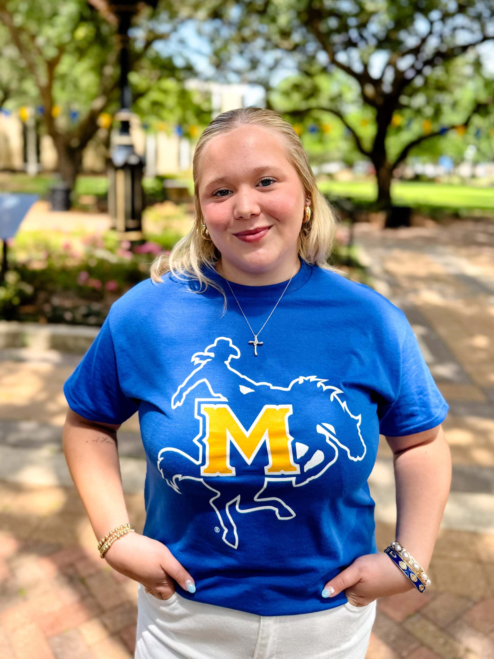 Ally Friesner smiling outdoors in front of Clock Tower, wearing a blue and yellow T-shirt.