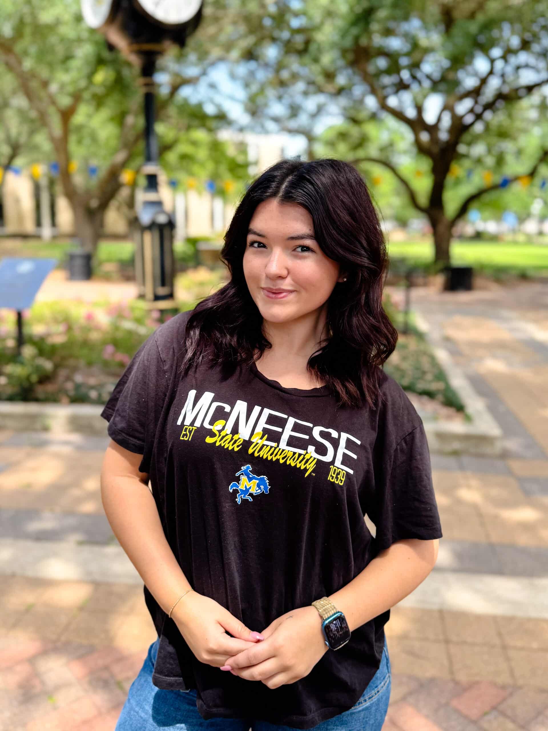 Calista Netherland smiling outdoors in front of Clock Tower, wearing a black T-Shirt.