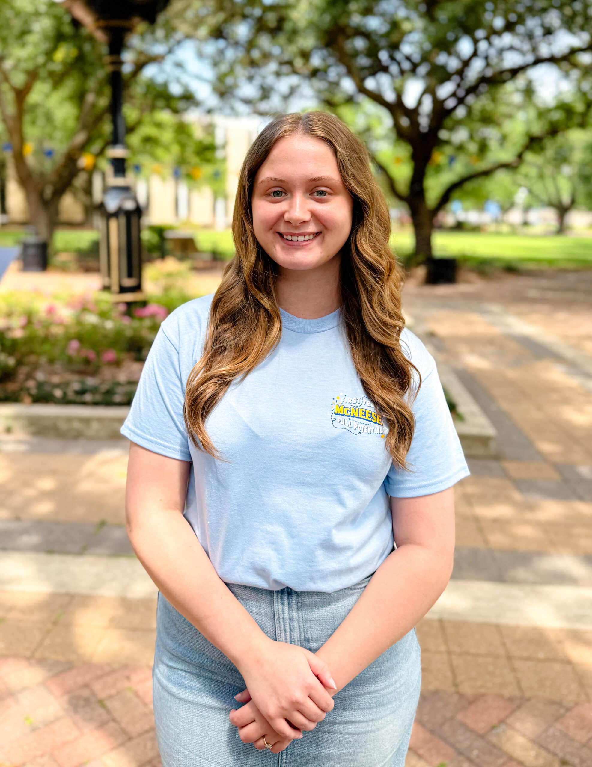 Emmah Fontenot smiling outdoors in front of Clock Tower, wearing a light blue T-shirt.