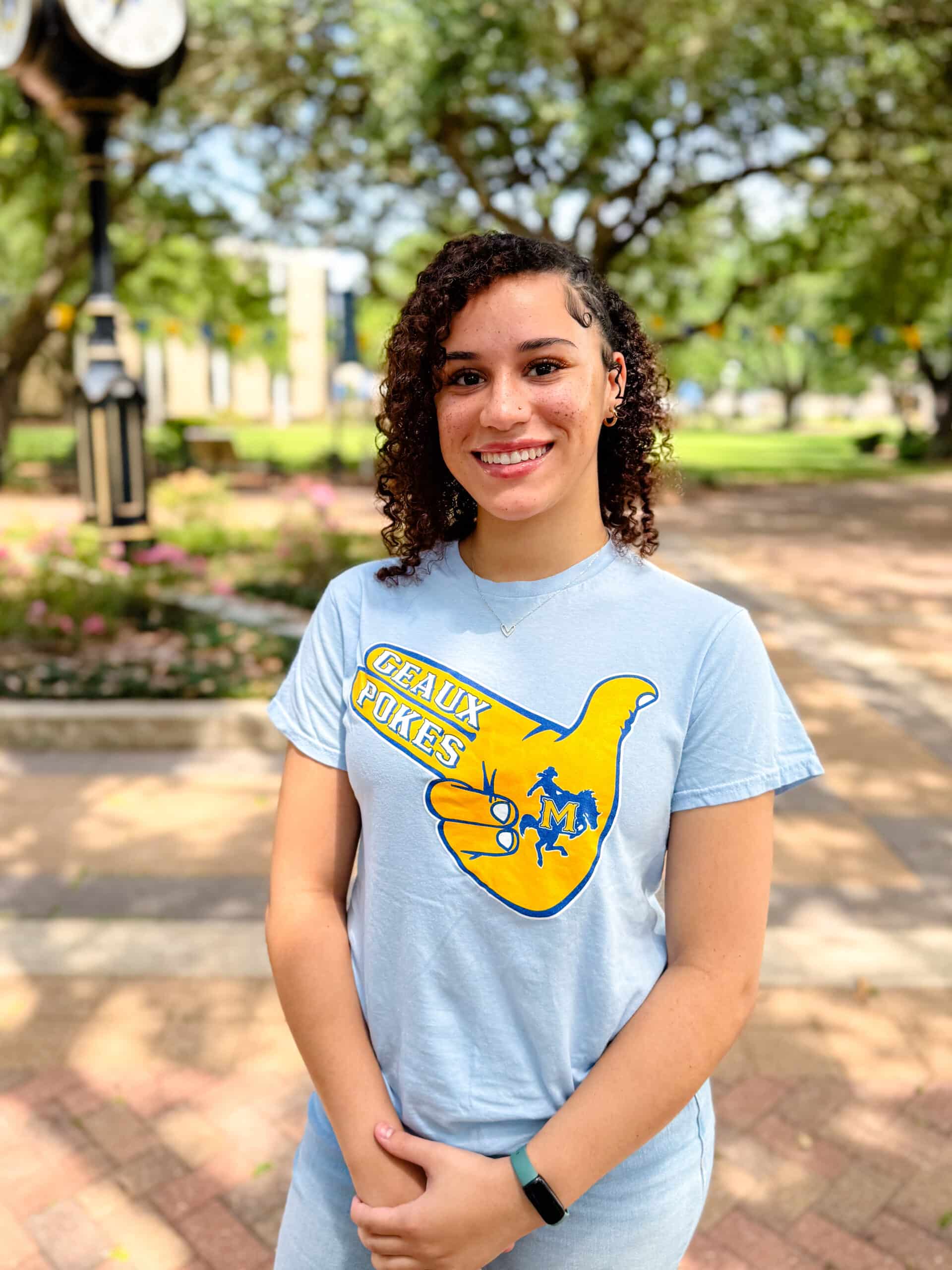 Gilayia Begnaud smiling outdoors in front of Clock Tower, wearing a light blue T-shirt.